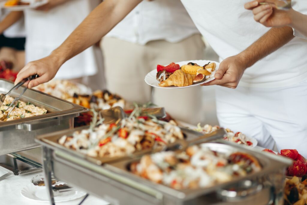 Hands Taking Food from a Table at a Swedish Buffet Party